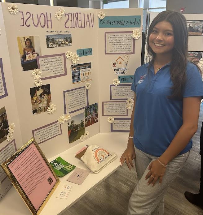 Teen ambassador presenting a Valerie’s House project display at school