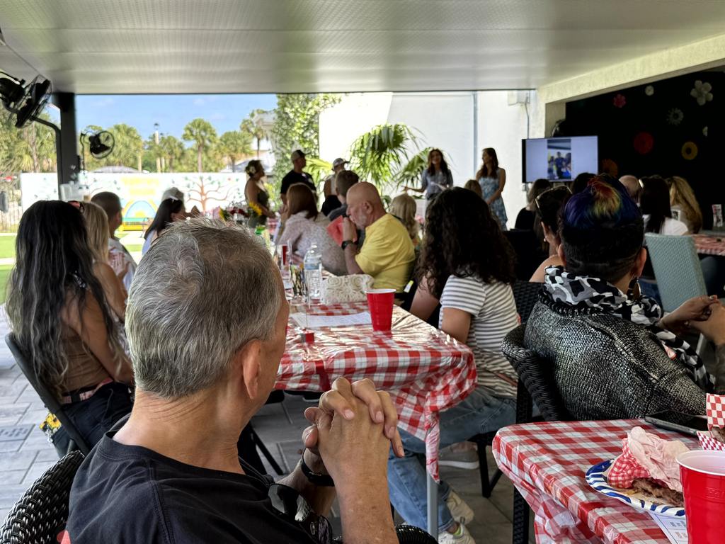 Volunteers seated and listening during a presentation at Valerie’s House appreciation event