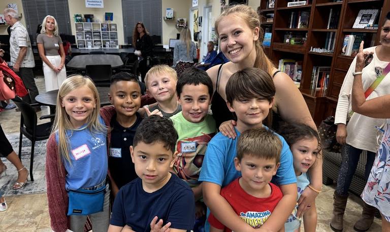 Group of kids and a volunteer smiling together during a Valerie’s House group night.