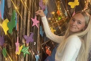Molly Flynn hangs a leaf on the memory tree at Valerie’s House Fort Myers Family is Forever Home in honor of her father, an Air Force veteran