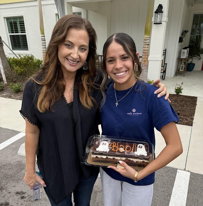 Briza smiles with Angela Melvin at Valerie’s House while holding a cake.
