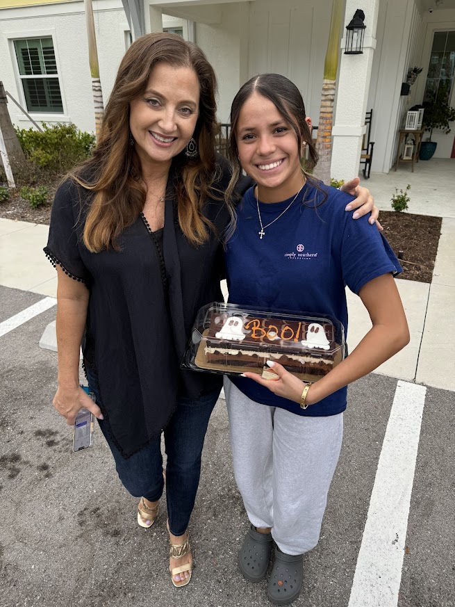 Briza smiles with Angela Melvin at Valerie’s House while holding a cake.