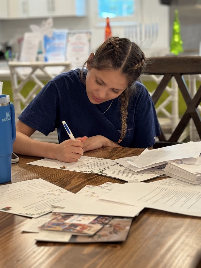 Briza writes cards at a table inside Valerie’s House.