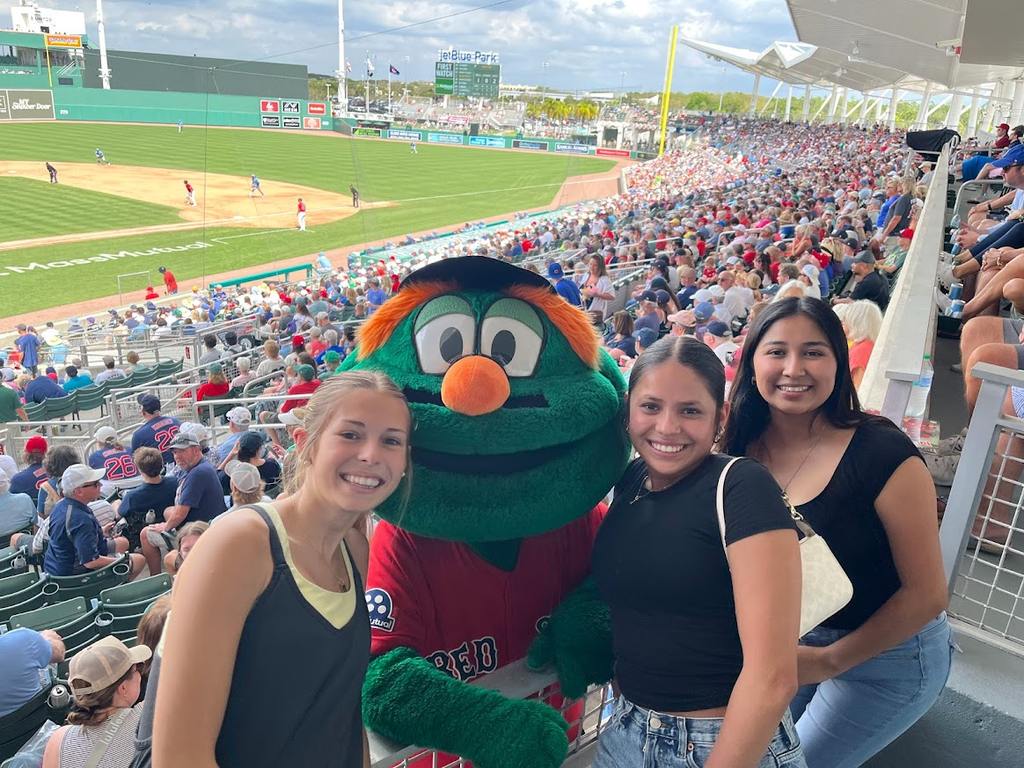 Briza smiles with friends and a mascot at a baseball game.