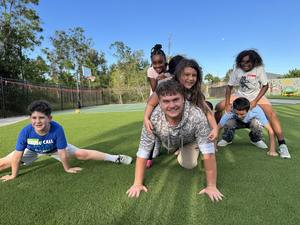 Valerie’s House Teen Ambassador Carter plays outside with kids during a group night.