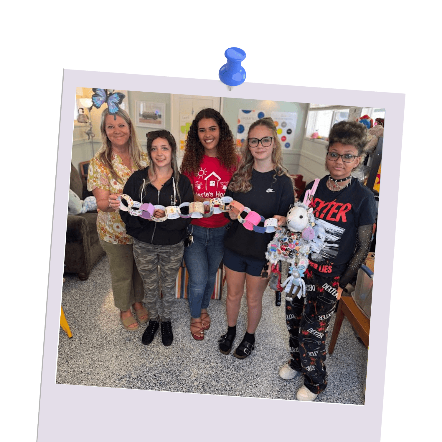 Kids and teen ambassadors at Valerie’s House holding a colorful paper chain during a group activity at the Fort Myers Family is Forever Home